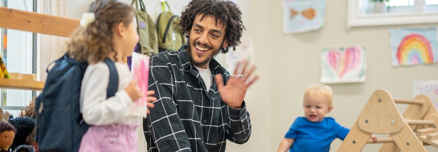 a young child waves goodbye to her daycare teacher