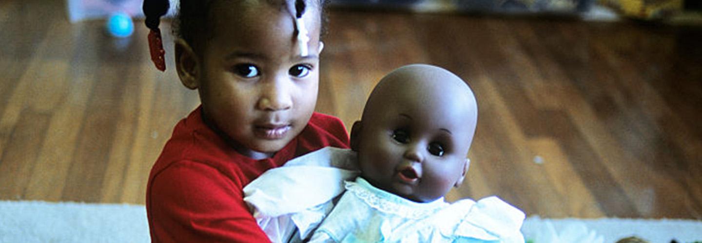 A young girl holds a baby doll