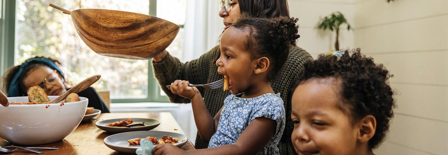 a mother passes the salad bowl at dinner