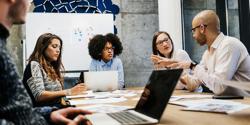 a group of people sit around a table in a meeting