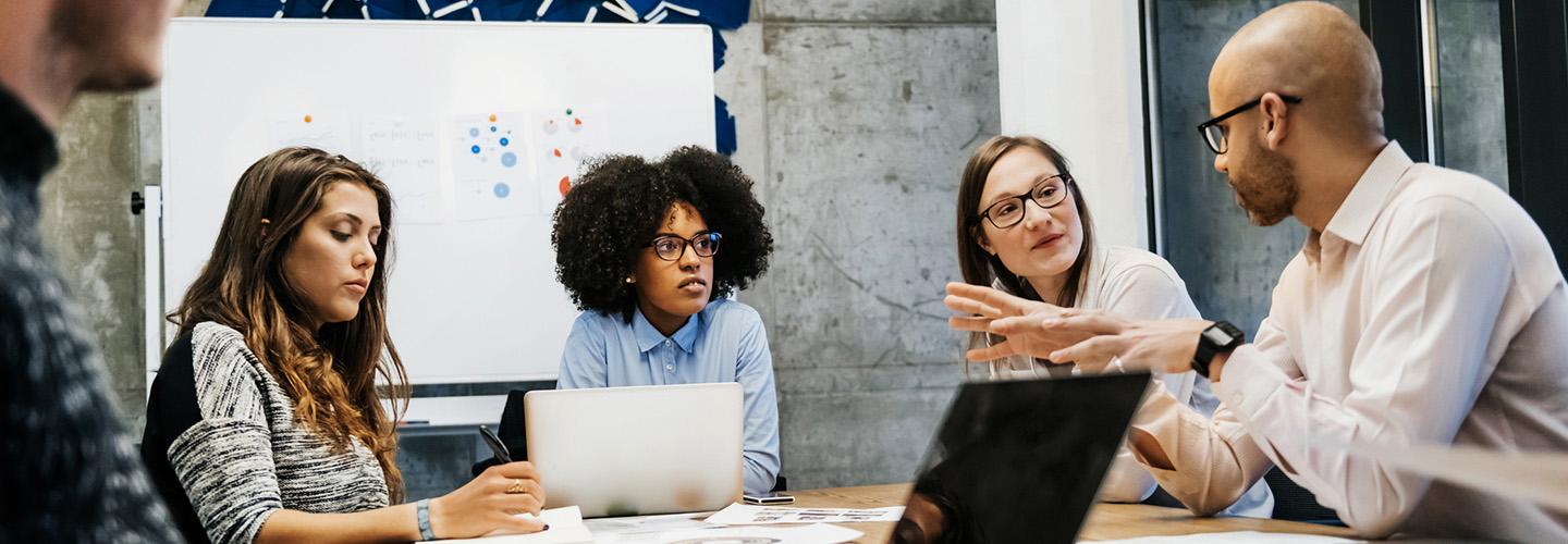 a group of people sit around a table in a meeting