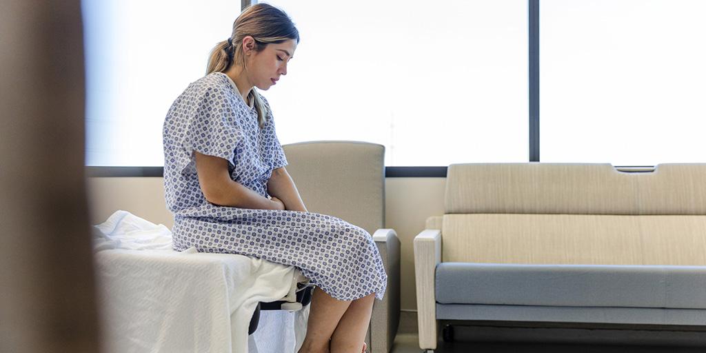 a young woman in a hospital gown waits in the doctor's office