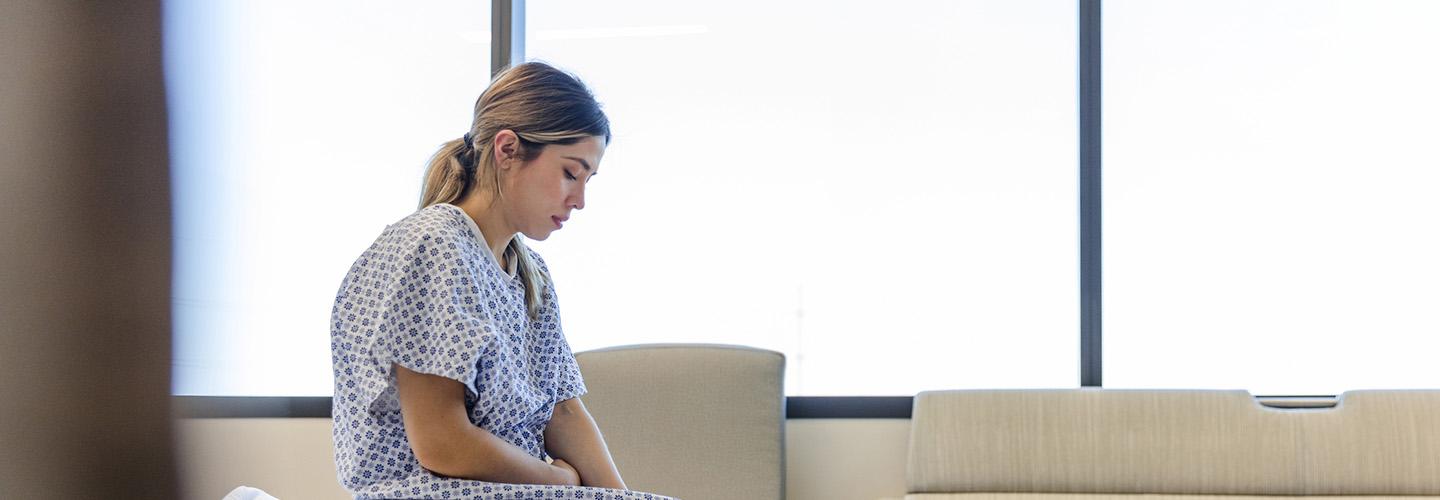 a young woman in a hospital gown waits in the doctor's office