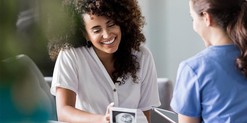 a woman shows a sonogram to a healthcare provider