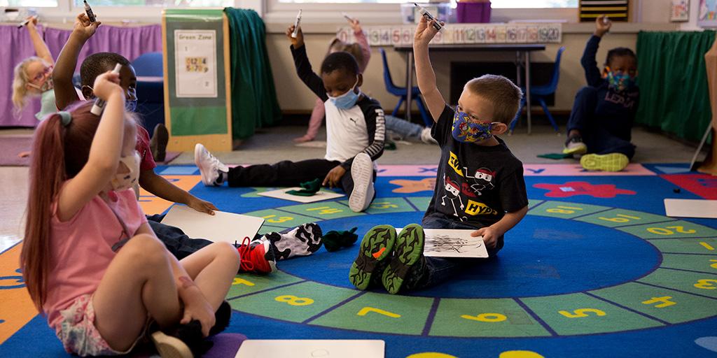 young children sit on a carpet in class