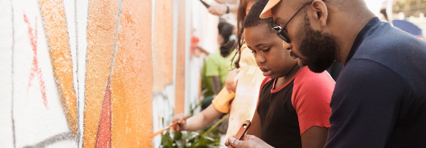 a father and son help paint a mural