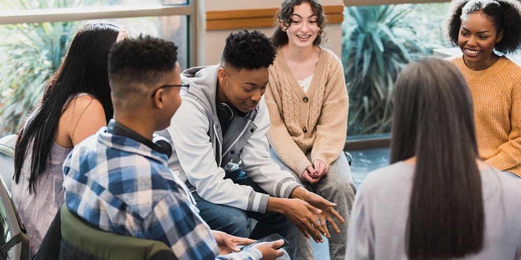 a young man talks in a group of peers