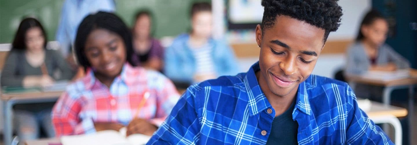 a young man works in a notebook in class