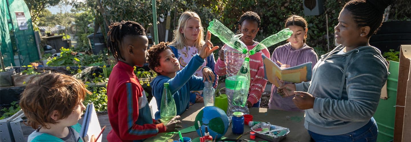 Group of school children making environmental art with their teacher
