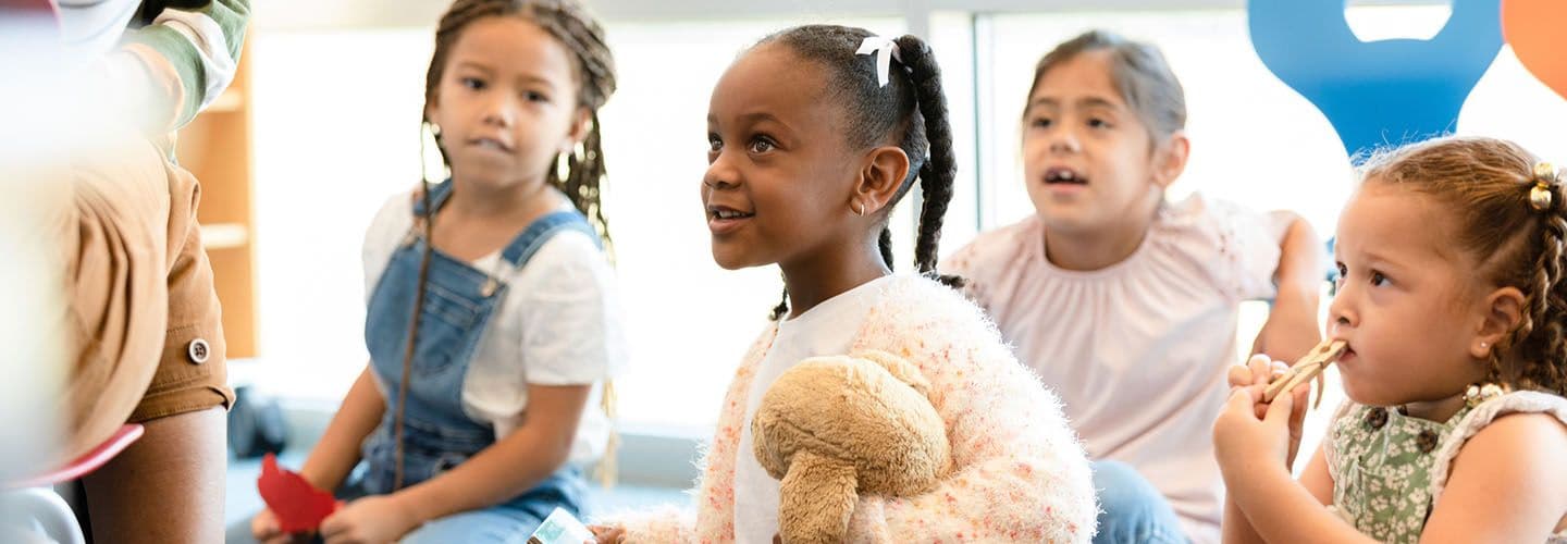 young kids sit on the carpet at daycare